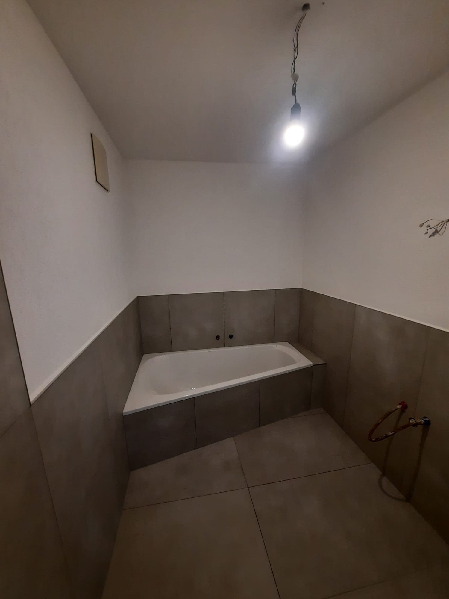Professionell verlegte Eckbadewanne mit modernen Großformatfliesen in Schieferoptik