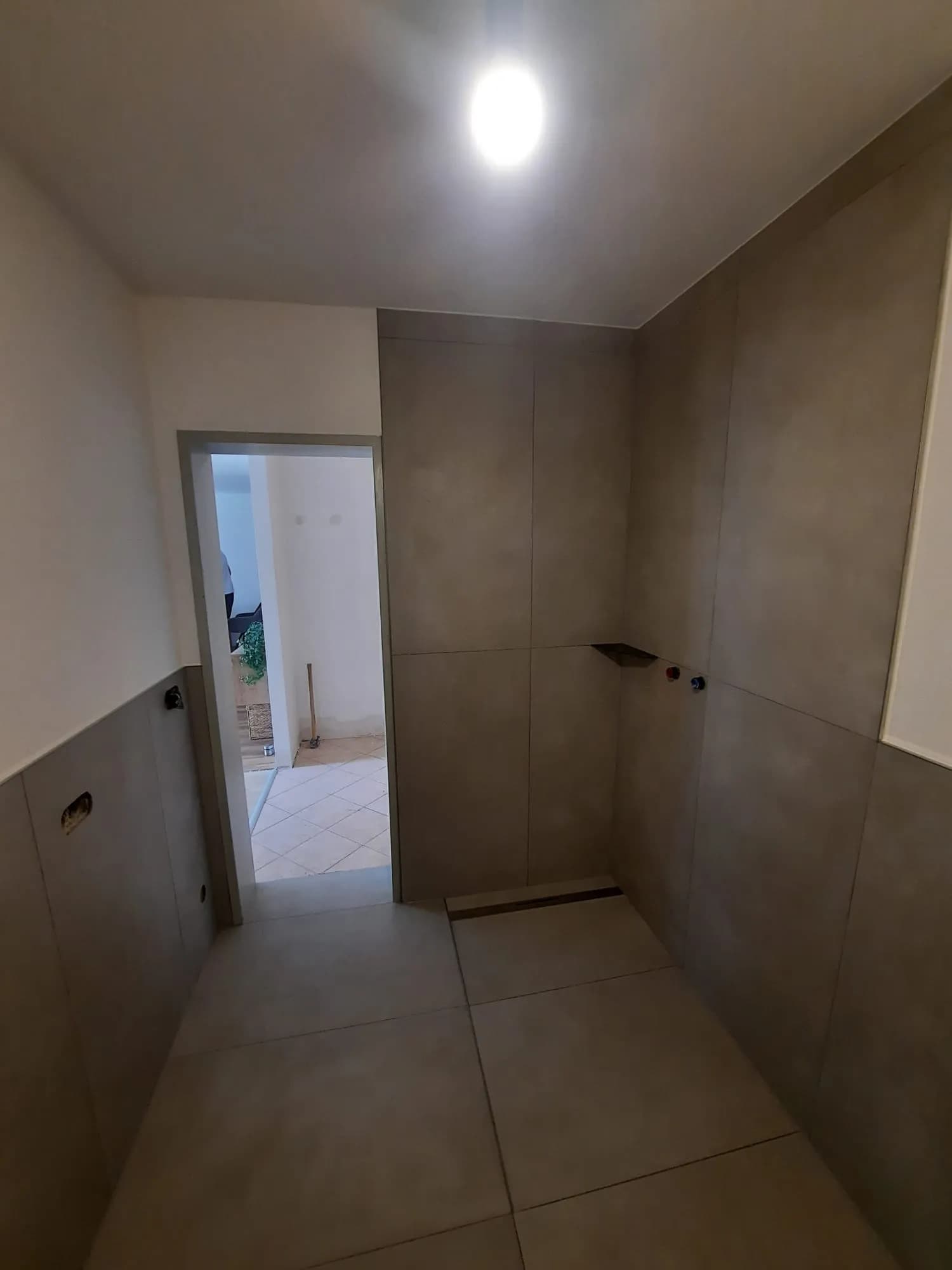 Professionell verlegte Eckbadewanne mit modernen Großformatfliesen in Schieferoptik 2