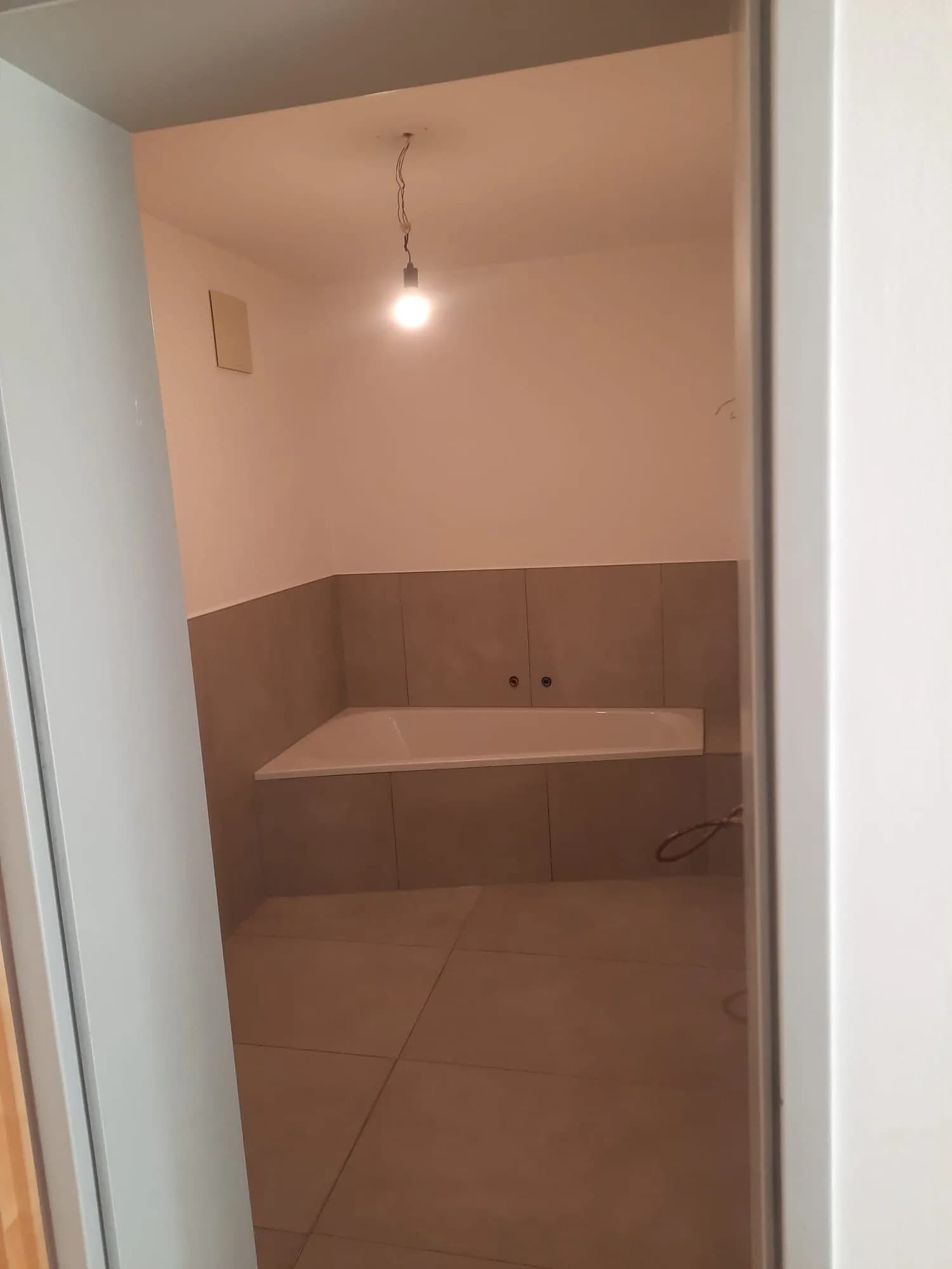 Professionell verlegte Eckbadewanne mit modernen Großformatfliesen in Schieferoptik 6