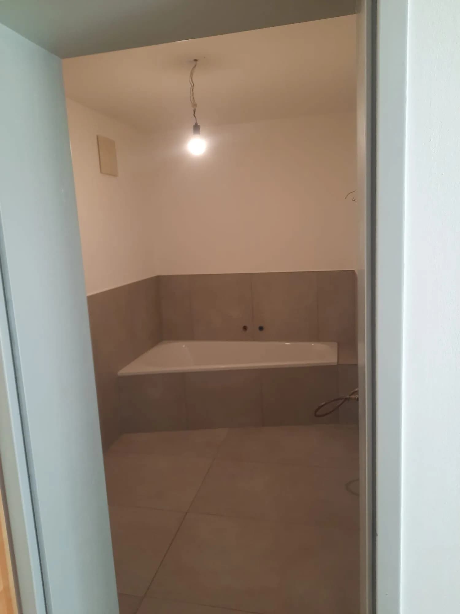 Professionell verlegte Eckbadewanne mit modernen Großformatfliesen in Schieferoptik 5