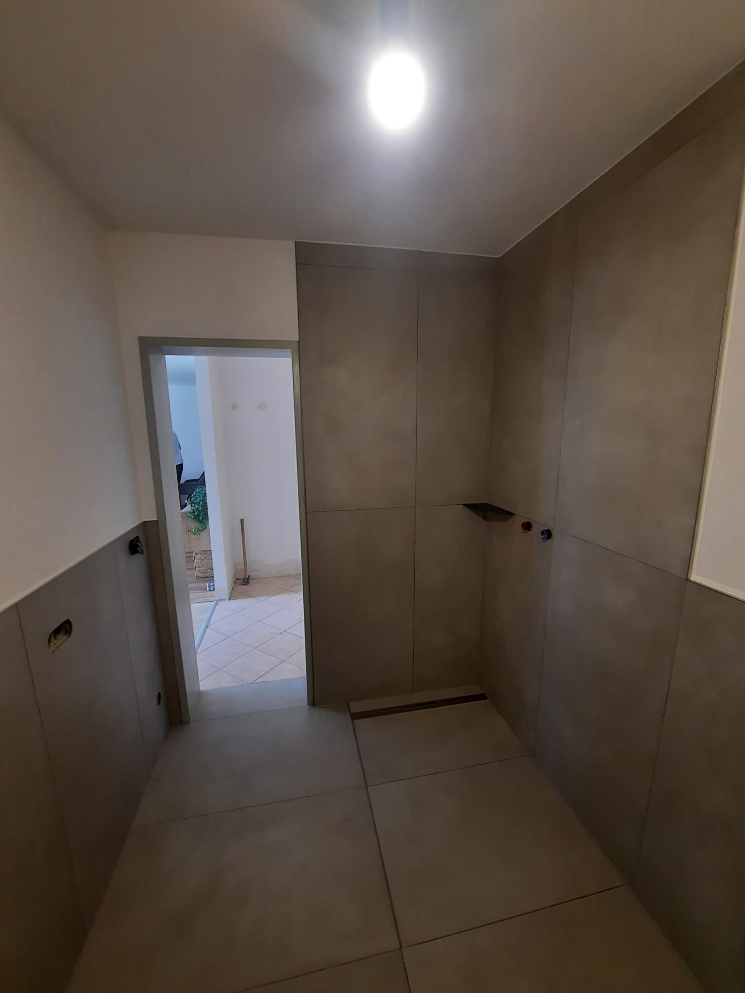 Professionell verlegte Eckbadewanne mit modernen Großformatfliesen in Schieferoptik