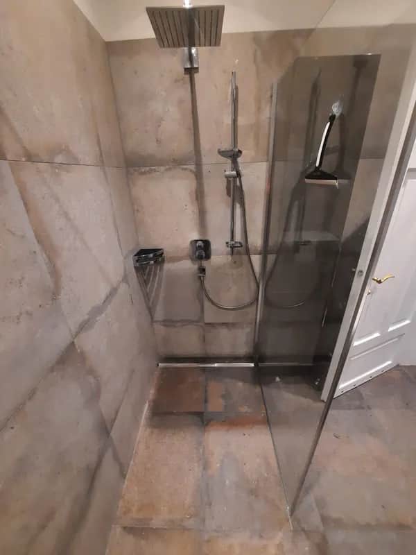 Rustikale Luxus-Dusche mit Natursteinfliesen und moderner Ausstattung